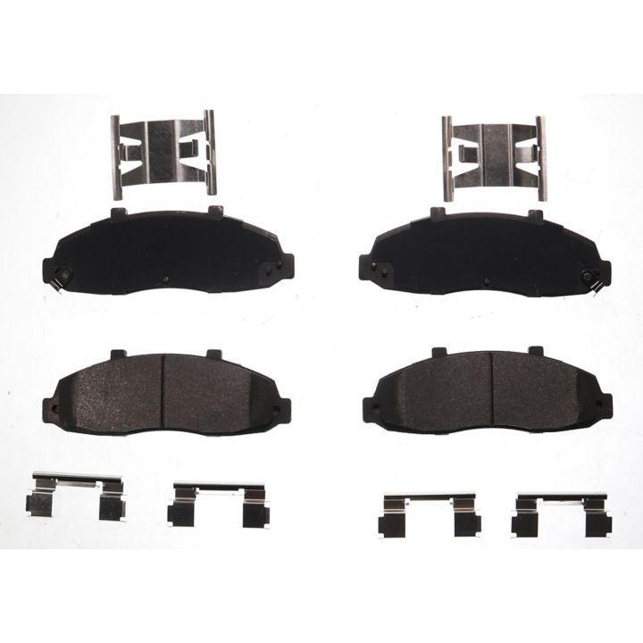 Four BFD679SM ProSeries OE Brake Pads in black, accompanied by metal clips and brackets, arranged on a white background.